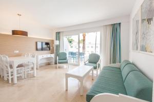 a living room with a couch and a dining room at Apartamentos Solecito in Port d'Alcudia