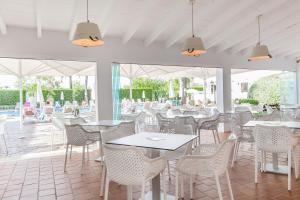 un restaurante con mesas y sillas blancas y un patio en Apartamentos Solecito, en Puerto de Alcudia