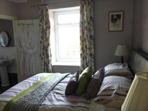a bedroom with a bed and a window with a dress hanging in at The Clytha Arms in Abergavenny