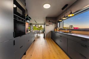 a kitchen with gray cabinets and a large window at Villa Walter Lofoten with SAUNA in Kvalnes