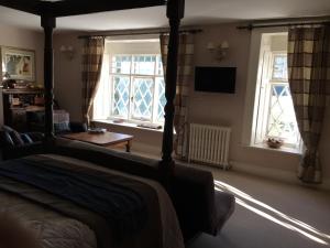 a bedroom with a bed and two windows at The Clytha Arms in Abergavenny