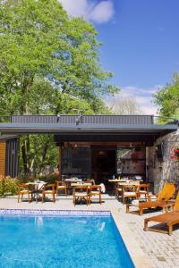 a pool with tables and chairs next to a building at Blisku do Gradot - Riverfront Luxury Cabins in Skopje