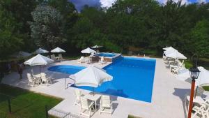a swimming pool with chairs and umbrellas next to it at Cabañas Am Bach in Villa General Belgrano