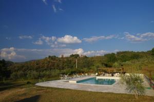 a swimming pool with tables and chairs next to a mountain at Mezzano In Chianti in Strada