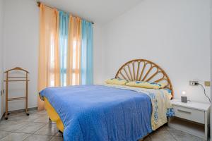 a bedroom with a bed with a blue blanket and a window at Villetta Vespucci in Agrustos