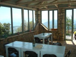 two tables and chairs in a room with windows at Merlot Village Rental Apartments in Kariá