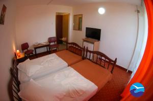 a bedroom with two beds and a table and a television at Hotel Traian Eforie Nord in Eforie Nord