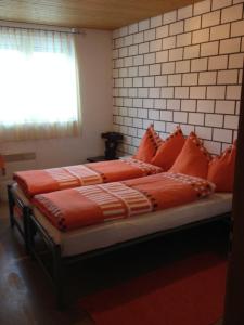 a bed with orange pillows on it in a room at La Cantina Restaurant in Alvaneu