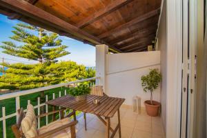 a balcony with a wooden table and chairs and a tree at Kondarini's Sea View Studios in Tsilivi