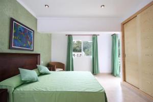 a bedroom with a green bed and a window at Can Medina in Pollença +18 photos