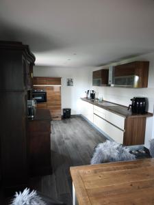 a kitchen with wooden cabinets and a wooden table at Haus am Deich in Norden +9 photos