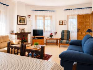 a living room with a blue couch and a tv at Private Pool Villa La Siesta in La Mata