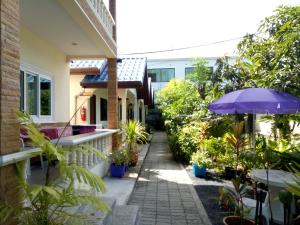 ogród z roślinami i parasolem na domu w obiekcie Wattana Bungalow w mieście Nai Yang Beach
