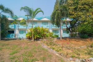 a large white building with palm trees and plants at Koh Lak Resort in Prachuap Khiri Khan