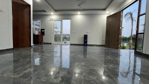 an empty room with a concrete floor and large windows at Vijay Laxmi Farm House in Manjhāoli