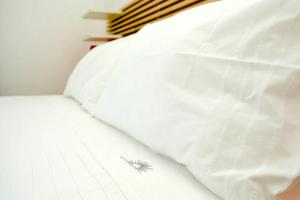 a white bed with a feather on the side of it at La Casa del Riccio in Tindari