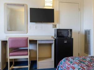 a room with a desk with a television and a bed at Loyalty Inn in Brice