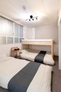 two beds in a room with white walls at Epilogue Hotel 202 in Fukuoka