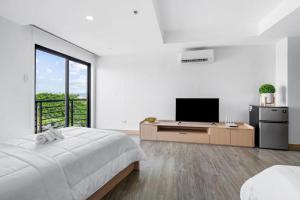 a white room with a bed and a television at Espacio Hotel in Manila