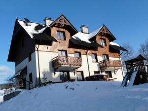 a large wooden house with snow on the ground at W Cieniu Akacji in Jaworki