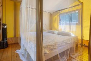 a bedroom with a canopy bed with white curtains at Lodge La Forêt in Saint-Sauveur +20 photos
