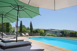 a pool with chairs and umbrellas next to a swimming pool at Lodge La Forêt in Saint-Sauveur