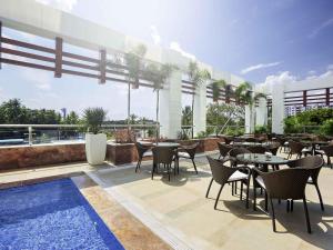 a restaurant with tables and chairs and a swimming pool at Novotel Chennai Sipcot in Chennai