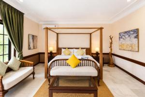 a bedroom with a bed and a couch at Frangipani Langkawi Resort in Pantai Cenang