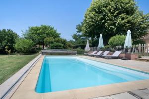 a swimming pool with chairs and umbrellas at Lodge Les Étoiles in Saint-Sauveur