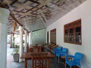 a dining room with wooden tables and blue chairs at Canal Side Guest House Polonnaruwa in Polonnaruwa