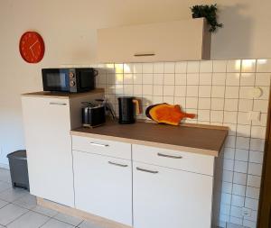 a kitchen with white cabinets and a microwave on a counter at Ferienwohnung Mika in Bad Rothenfelde +5 photos