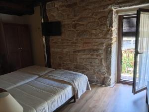a bedroom with a bed and a stone wall at Casa da Eira in Lobios
