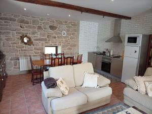 a living room with a white couch and a kitchen at Casa da Eira in Lobios