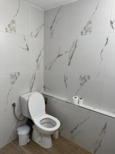 a bathroom with a white toilet and marble walls at Adela's Saranda Central Apartment in Sarandë +10 photos