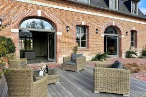 a patio with wicker chairs and a cat sitting on a deck at Maison proche Baie de Somme & Le Tréport-Terrasse in Biencourt