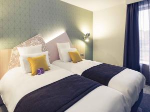 two beds in a hotel room with yellow and blue pillows at Hôtel Mercure Thionville Centre Porte du Luxembourg in Thionville