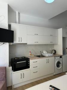 a kitchen with white cabinets and a black microwave at Adela's Saranda Central Apartment in Sarandë