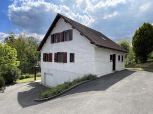 a white house with red windows on a driveway at Biena in Musculdy