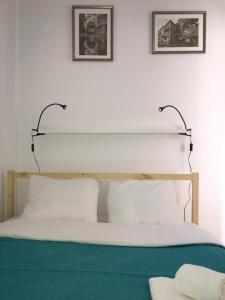 リスボンにあるCasa de Cimaのベッド1台(白い枕付)、壁に2枚の絵が飾られています。