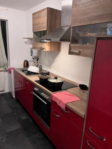 a kitchen with red cabinets and a stove with two pans at Kenny's place in Essen