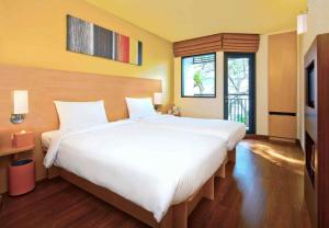 a large white bed in a room with a window at Ibis Hua Hin in Hua Hin