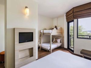 a bedroom with a bunk bed with a tv and a window at Ibis Hua Hin in Hua Hin