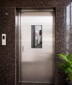 a silver elevator door in a building at Hotel Narsingi in Gundipet