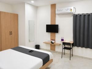 a bedroom with a bed and a tv and a desk at Hotel Narsingi in Gundipet