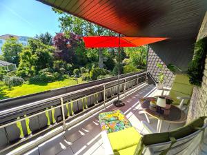 a balcony with a red umbrella and chairs and a table at Ferienwohnung Mika in Bad Rothenfelde