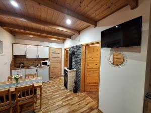 a kitchen and dining room with a flat screen tv on the wall at Domki Wichrowe Wzgórze Bieszczady in Bukowiec
