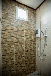 a bathroom with a shower with a brick wall at Naphet Resort in Phetchaburi
