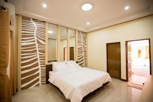 a bedroom with a white bed and a window at Naphet Resort in Phetchaburi