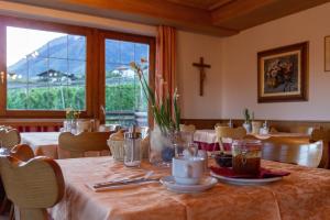 a dining room with a table and a cross on the wall at Garni An der Leit in Lagundo