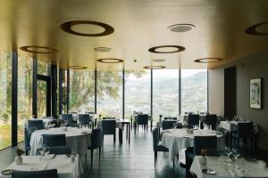 a dining room with tables and chairs and windows at Douro Palace Hotel Resort & SPA in Baião